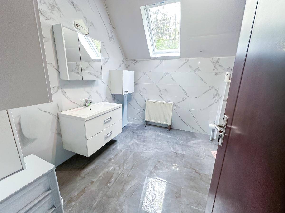 Modernes Badezimmer mit Marmorfliesen, Dachfenster und schwebendem Waschtischunterschrank.