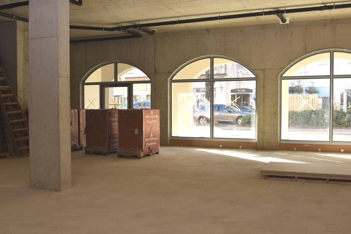 Rohbau eines Gewerberaums mit Betonstütze, großen Bogenfenstern und gestapelten Ziegeln.