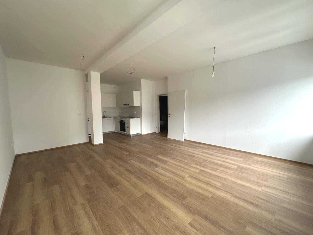 Offener Wohnbereich mit Laminatboden und Blick auf die moderne, integrierte Küchenzeile.