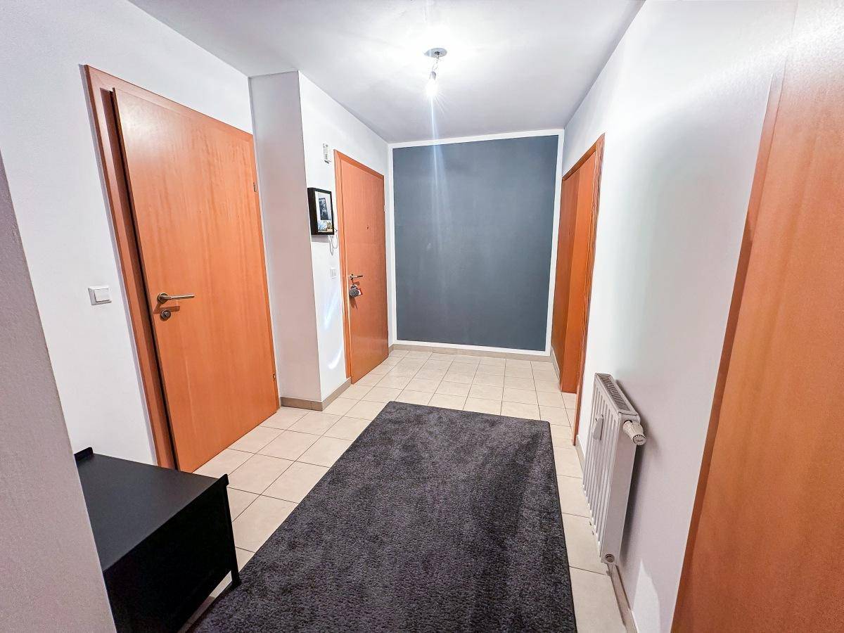 Heller Eingangsbereich mit Fliesenboden, Holztüren und Heizkörper.