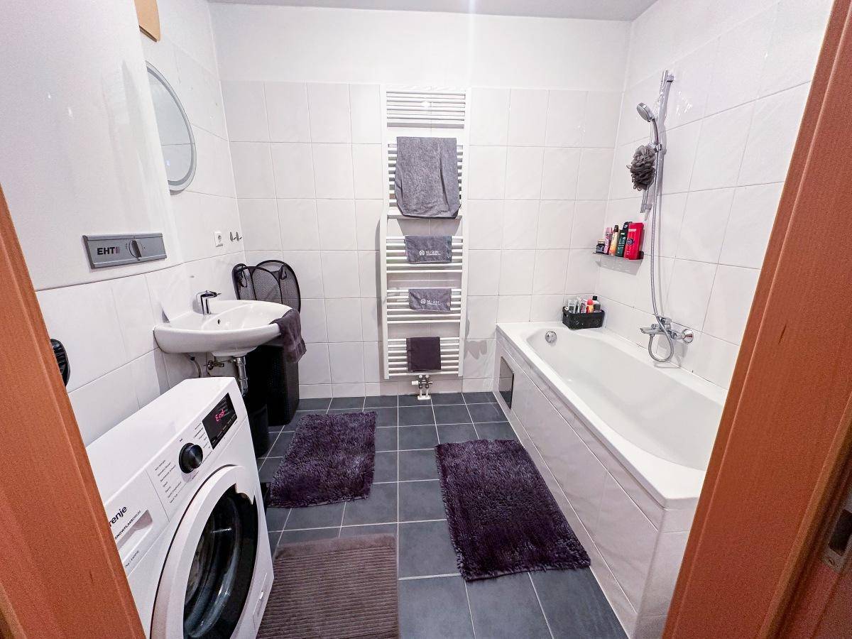 Modernes Badezimmer mit Badewanne, Dusche, Waschbecken und beheiztem Handtuchhalter.