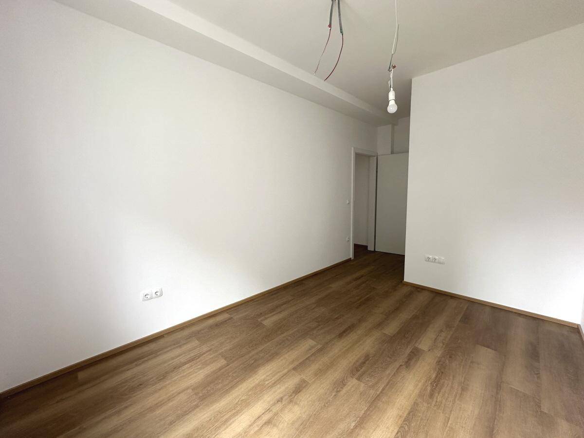 Unmöbliertes Wohnzimmer mit Laminatboden und weißen Wänden, bereit für die Einrichtung.