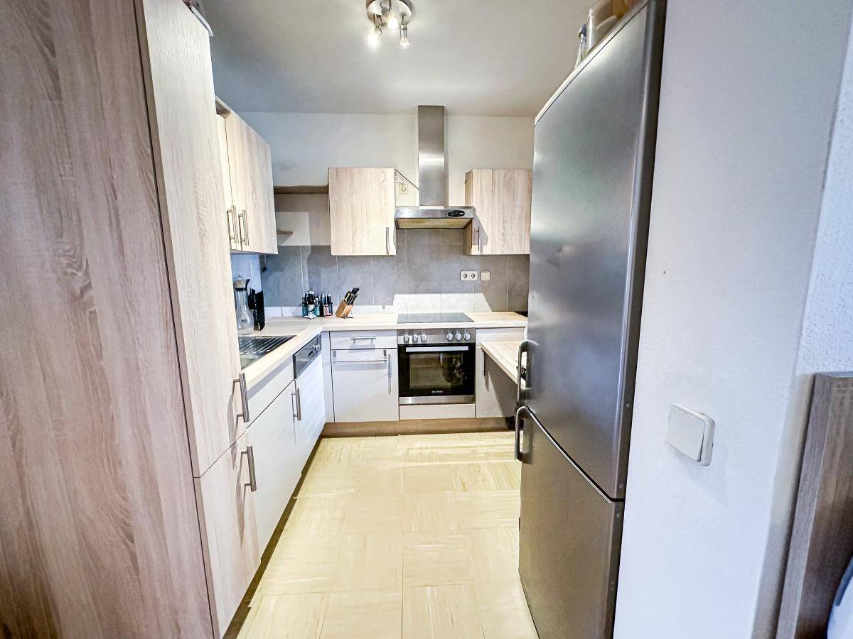 Moderne Küche mit hellen Holzfronten, Edelstahlgeräten und praktischer Anordnung.