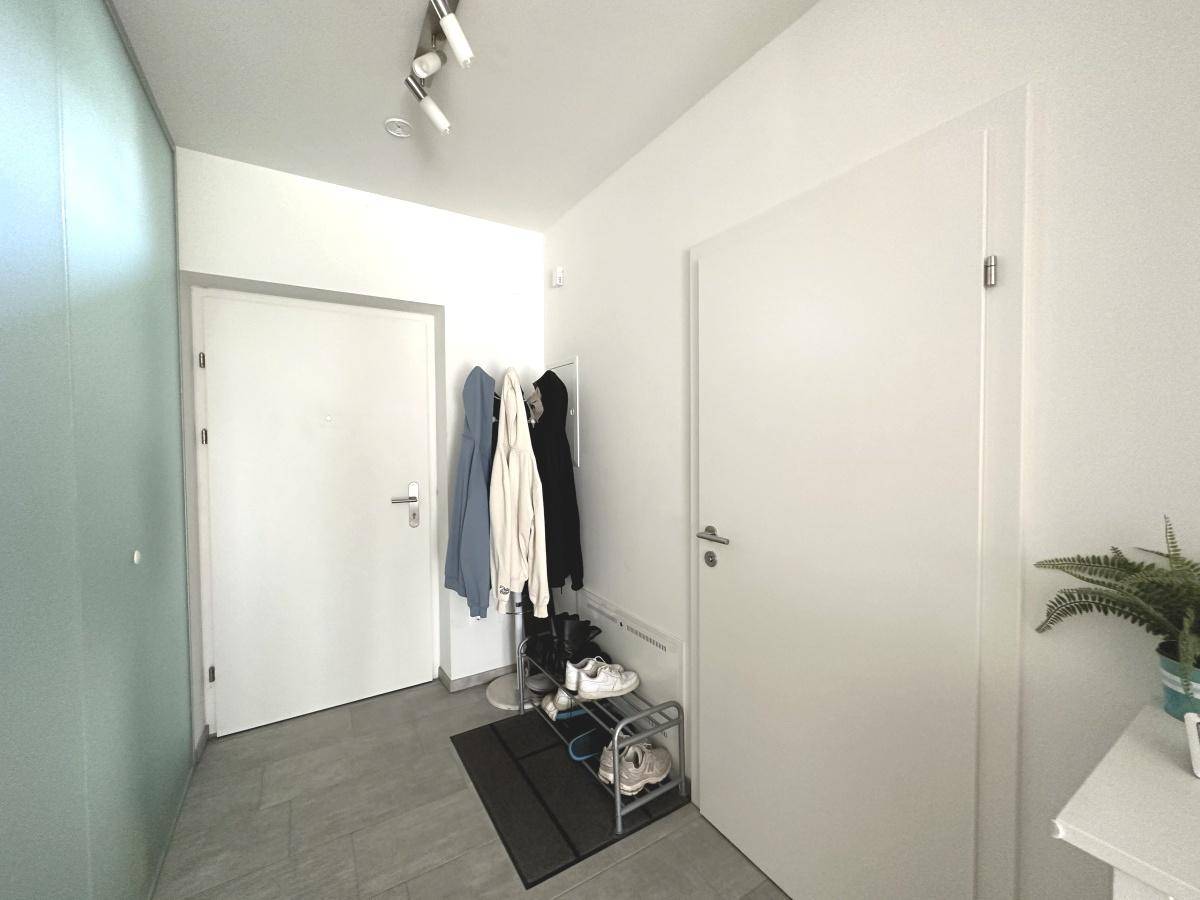 Heller Eingangsbereich mit Fliesenboden, Garderobe und Schuhregal.