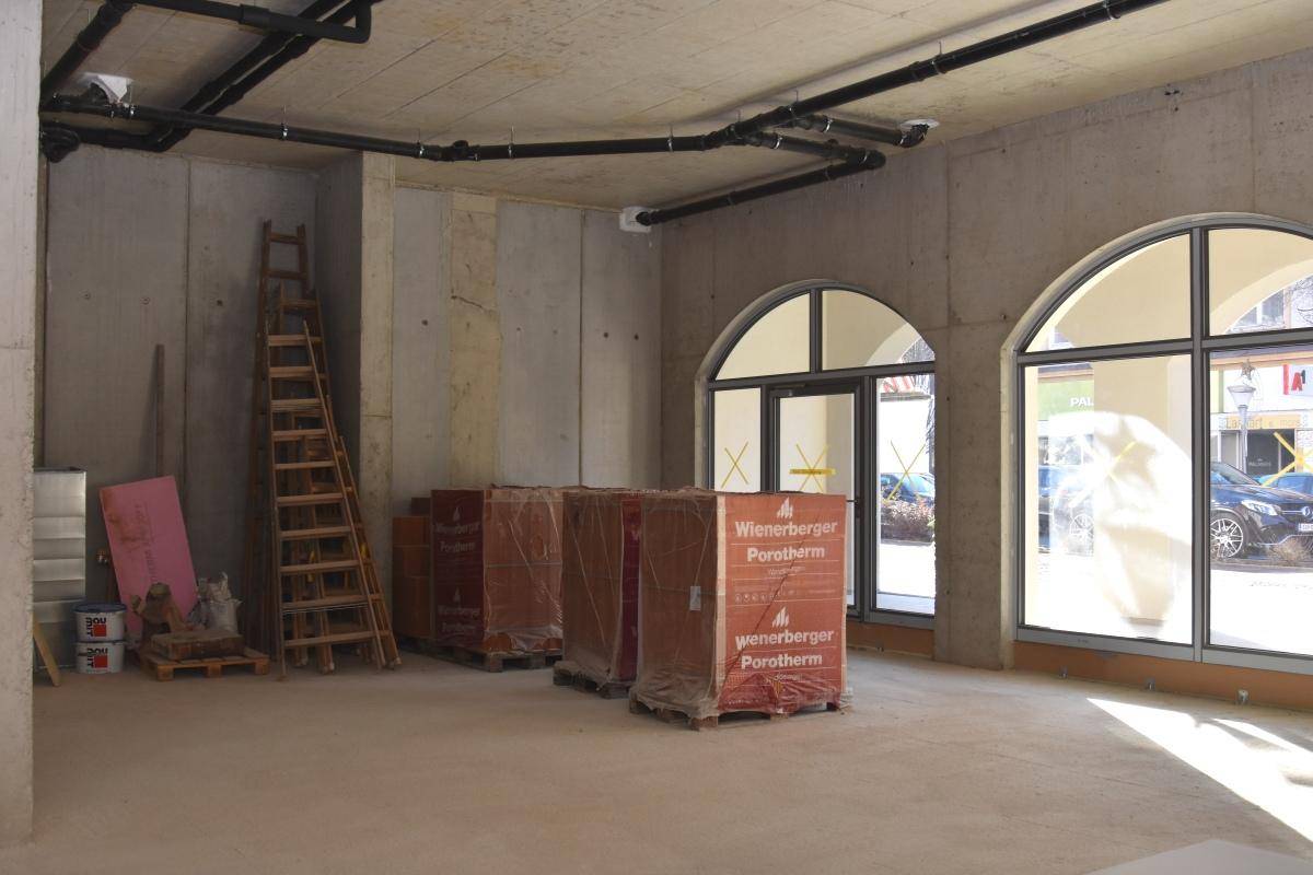 Geräumiger Rohbau mit Betonwänden, einer Leiter und großen Bogenfenstern, die viel Licht spenden.