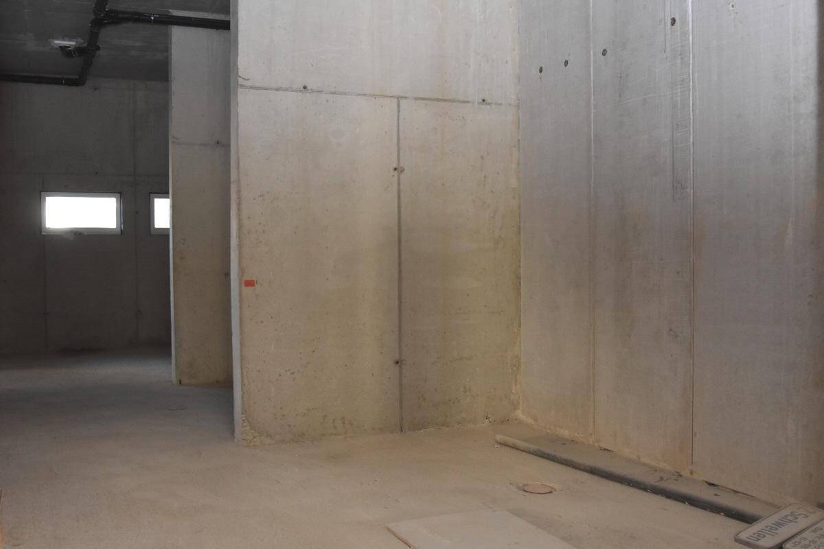Unfertiger Innenraum mit glatten Betonwänden und -boden, der auf den weiteren Ausbau wartet.