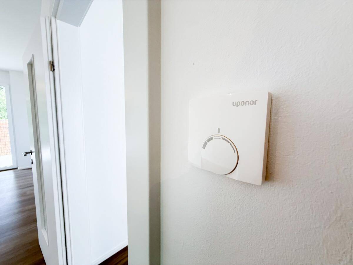 Wandthermostat zur Steuerung der Fußbodenheizung in einem modernen Wohnraum.