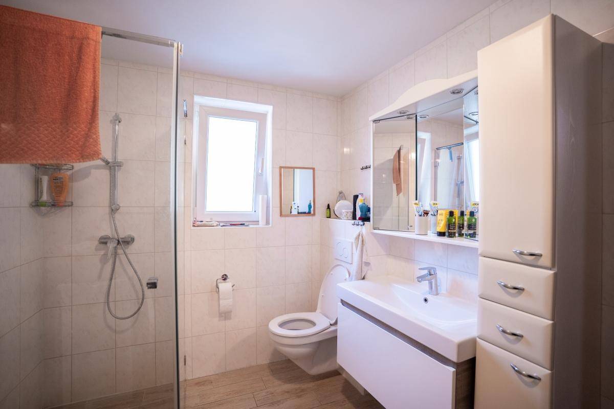 Helles Badezimmer mit Duschkabine, Waschtisch und Spiegelschrank.