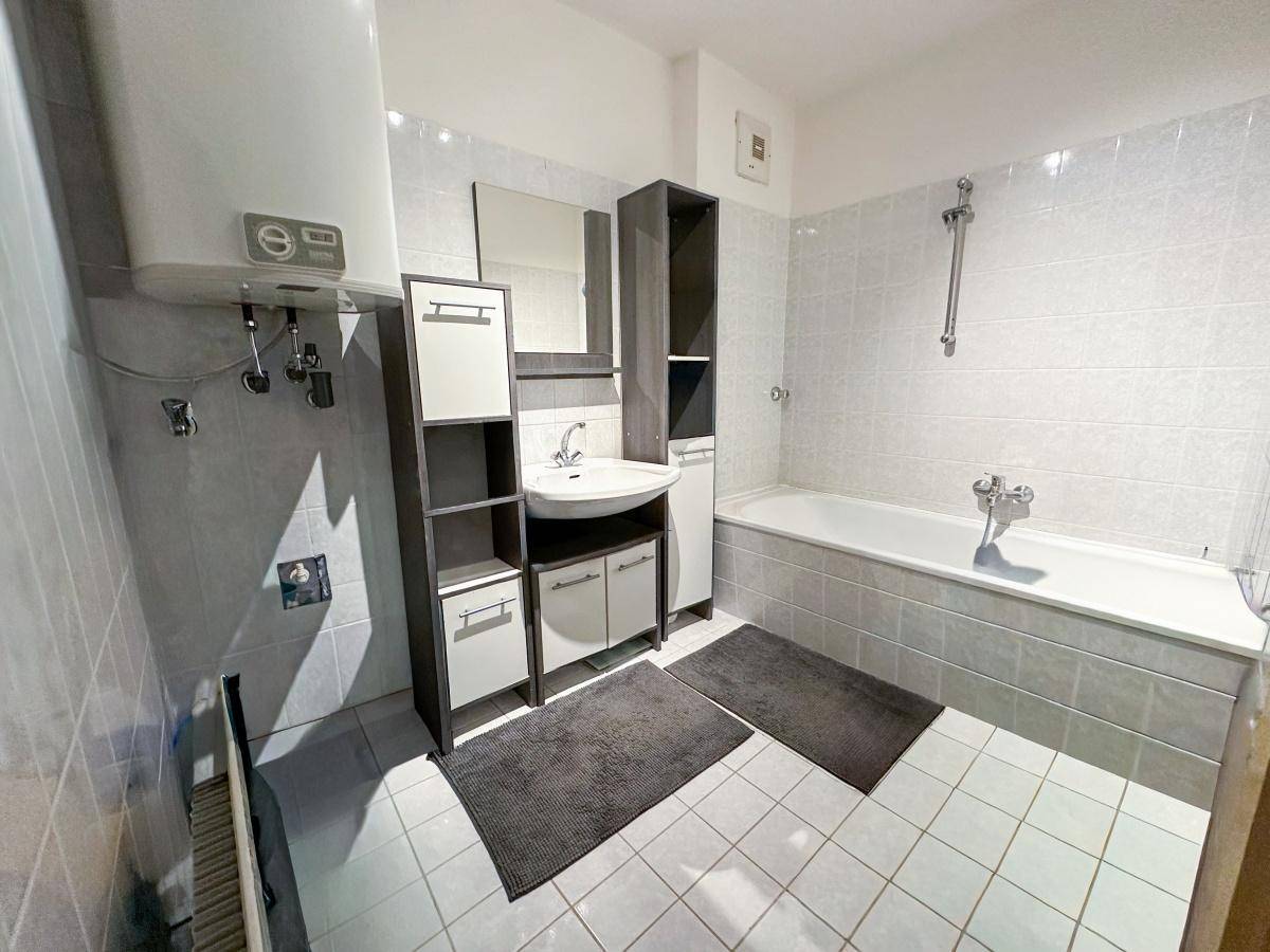 Badezimmer mit Badewanne, Duscharmatur, Waschbecken und Spiegelschrank.