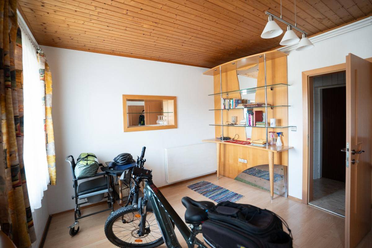 Schlafzimmer mit Holzbalkendecke, Fenster und Platz für ein Bett und Möbel.