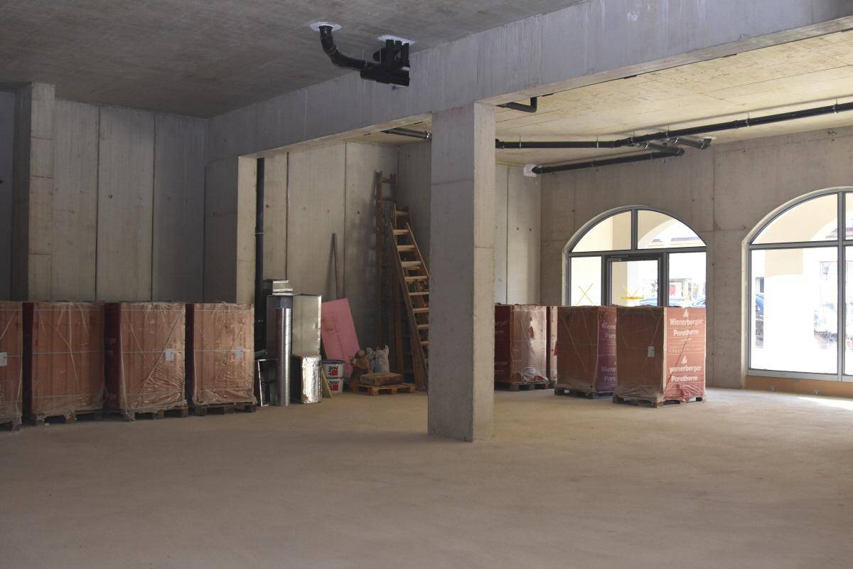 Großer Rohbau mit Betonwänden, Säulen und sichtbaren Installationen an der Decke, bereit für den Ausbau.