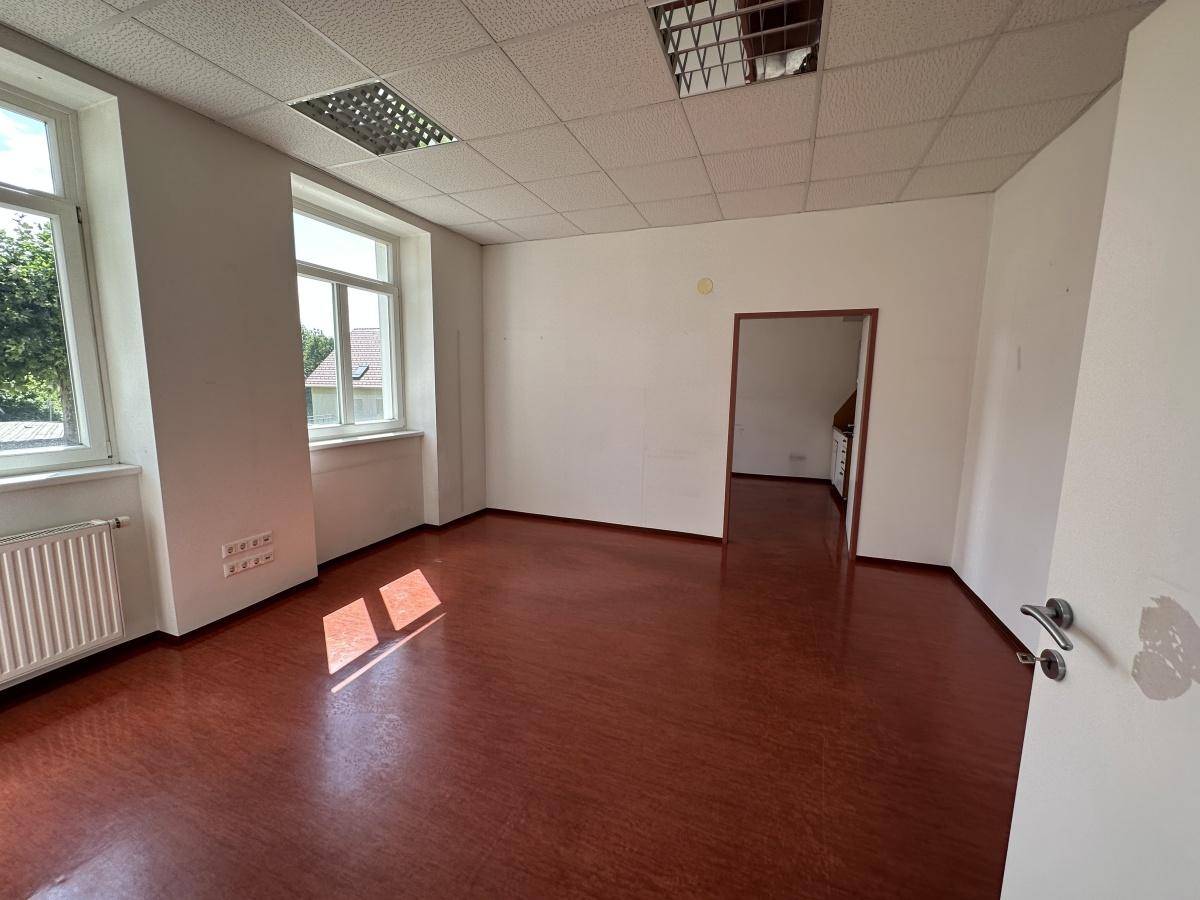 Heller Gewerberaum mit braunem Boden, weißen Wänden und Blick in einen weiteren Raum.