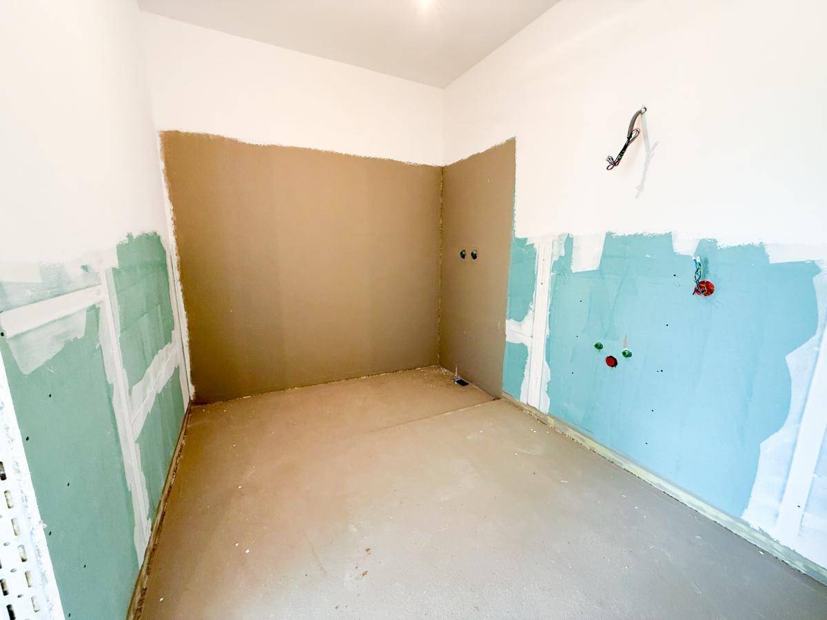 Unfertiges Badezimmer mit vorbereiteten Anschlüssen und Trockenbauwänden im Rohbauzustand.