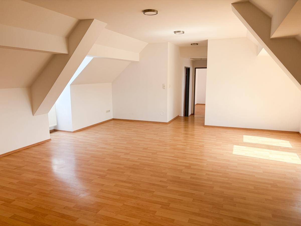 Geräumiger, heller Wohnbereich im Dachgeschoss mit Laminatboden und charakteristischen Dachschrägen.