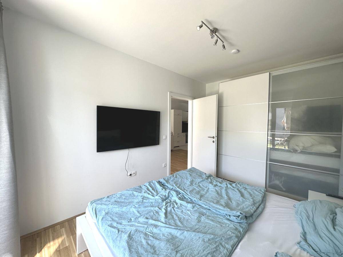 Schlafzimmer mit Doppelbett, Schiebetürenschrank und Fernseher an der Wand.