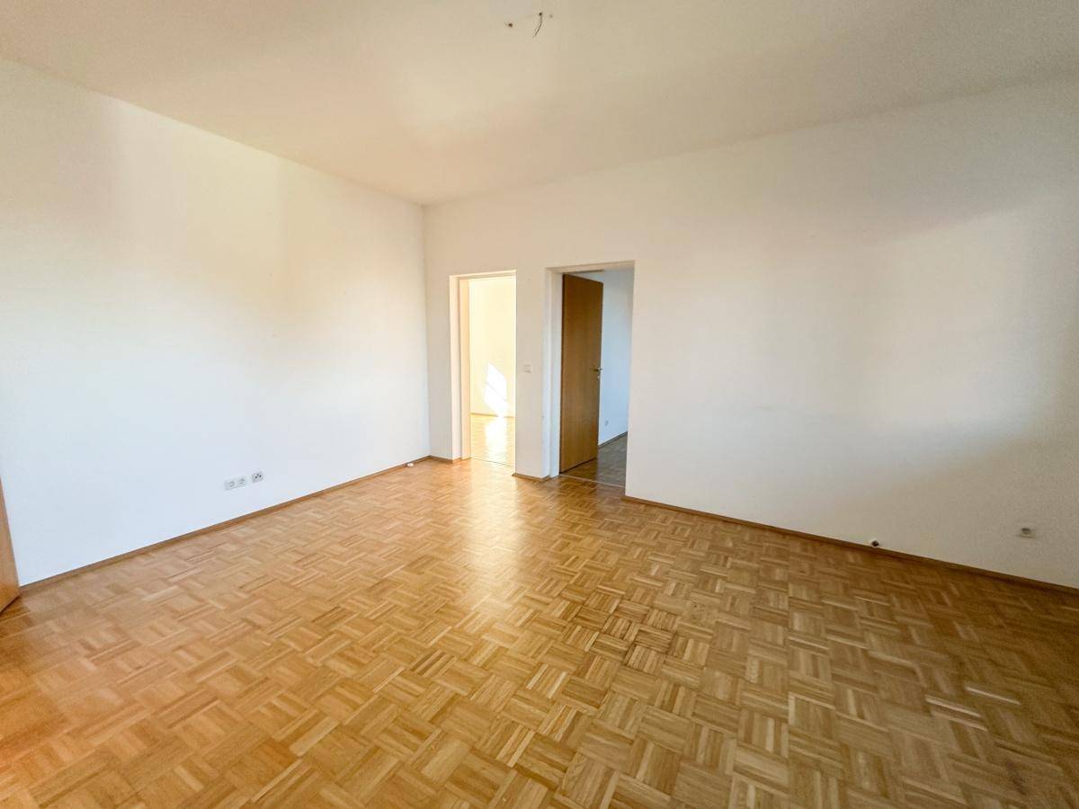 Geräumiges Zimmer mit hellem Parkettboden und weißen Wänden, bereit zur individuellen Gestaltung.