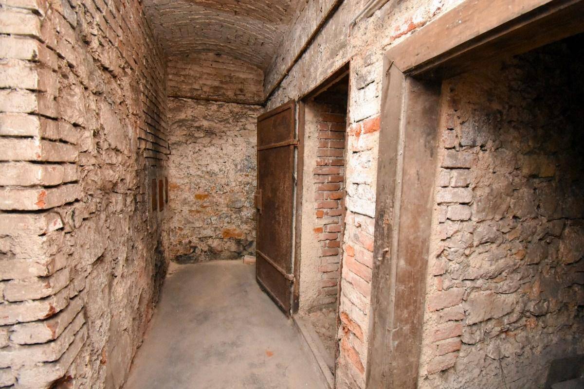 Historischer Kellerraum mit unverputzten Ziegelwänden, Gewölbedecke und alten Holztüren.