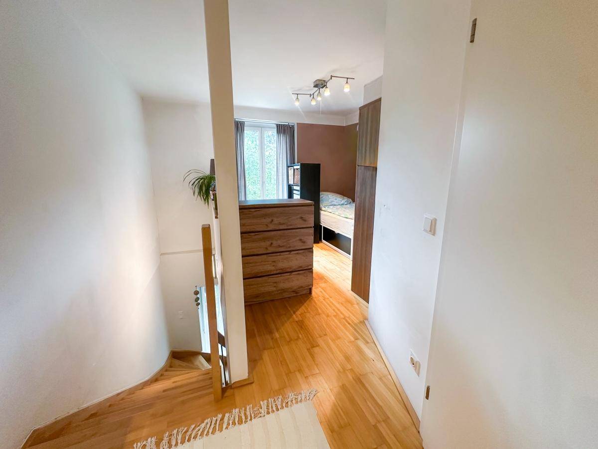 Heller Flur mit Holzboden und einer Kommode, der zu einem weiteren Zimmer führt.