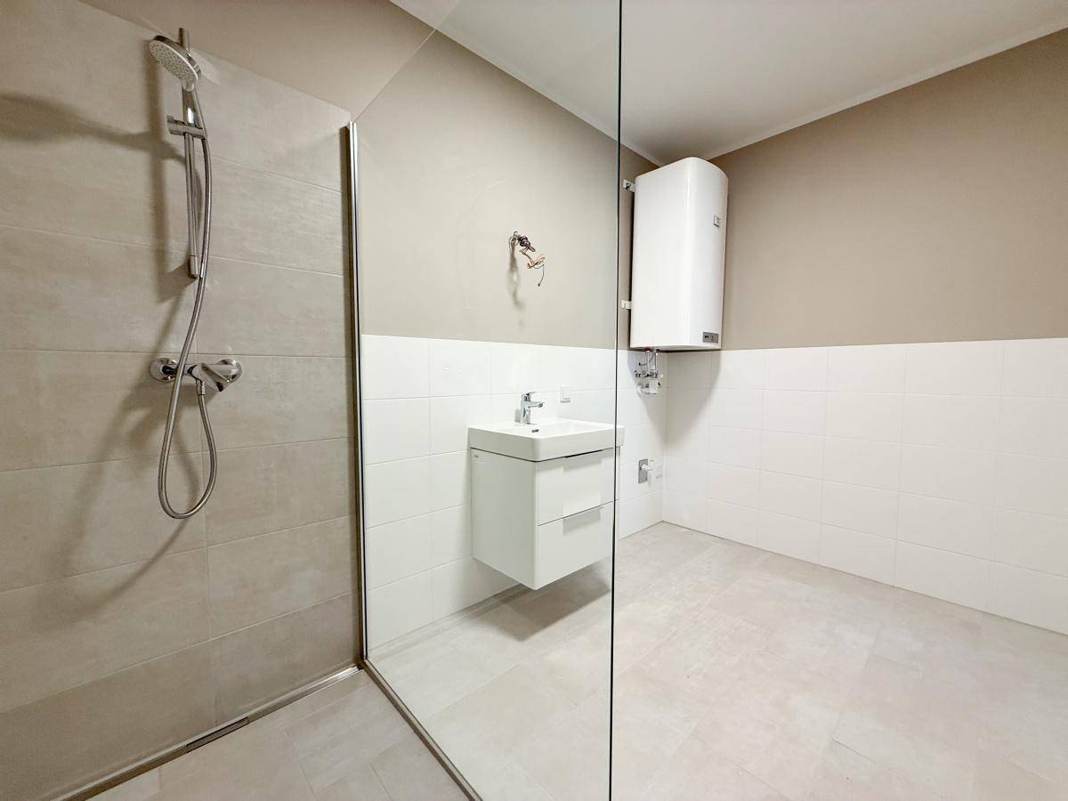 Modernes Badezimmer mit begehbarer Dusche, Waschbecken und Wandfliesen.
