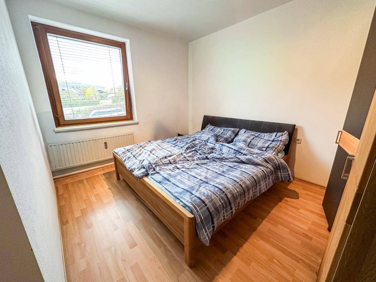 Schlafzimmer mit Doppelbett, Holzfußboden und Fenster für natürliches Licht.