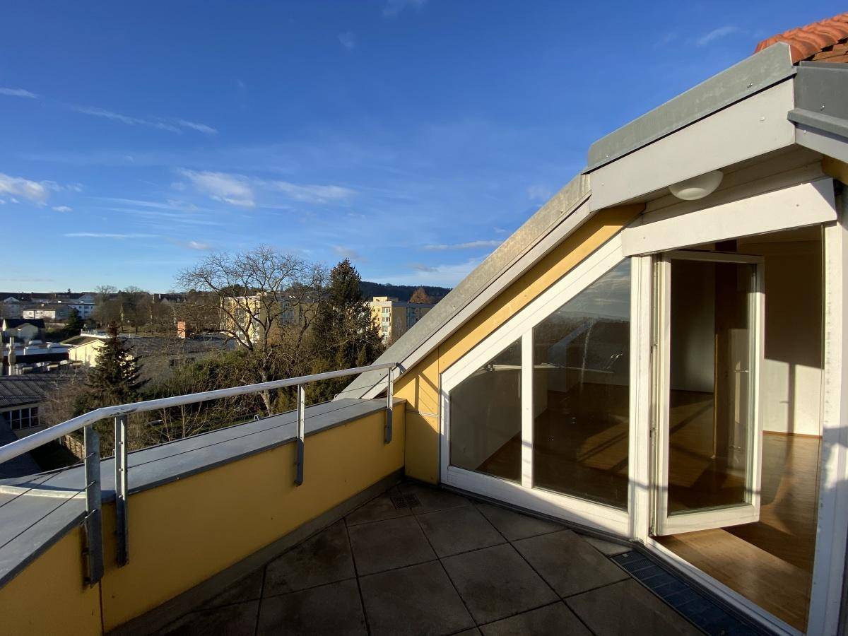 Geräumige Dachterrasse mit Fliesenboden, Metallgeländer und weitem Blick über die Umgebung.