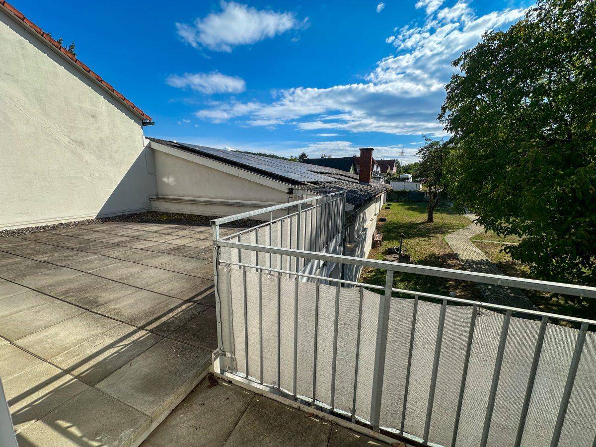 Große geflieste Terrasse mit Metallgeländer, bietet einen weiten Blick auf den Garten und die Umgebung.
