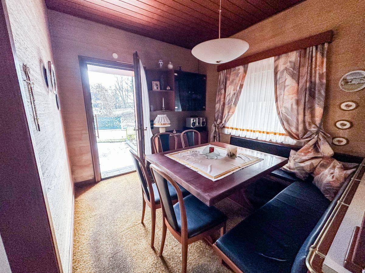Gemütlicher Essbereich mit Eckbank, Teppichboden und Zugang zum Garten.