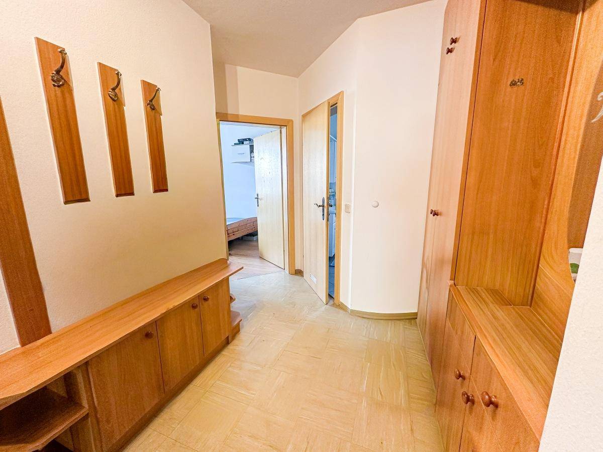 Heller Flur mit Holzmöbeln, Garderobe und Zugang zu weiteren Räumen.