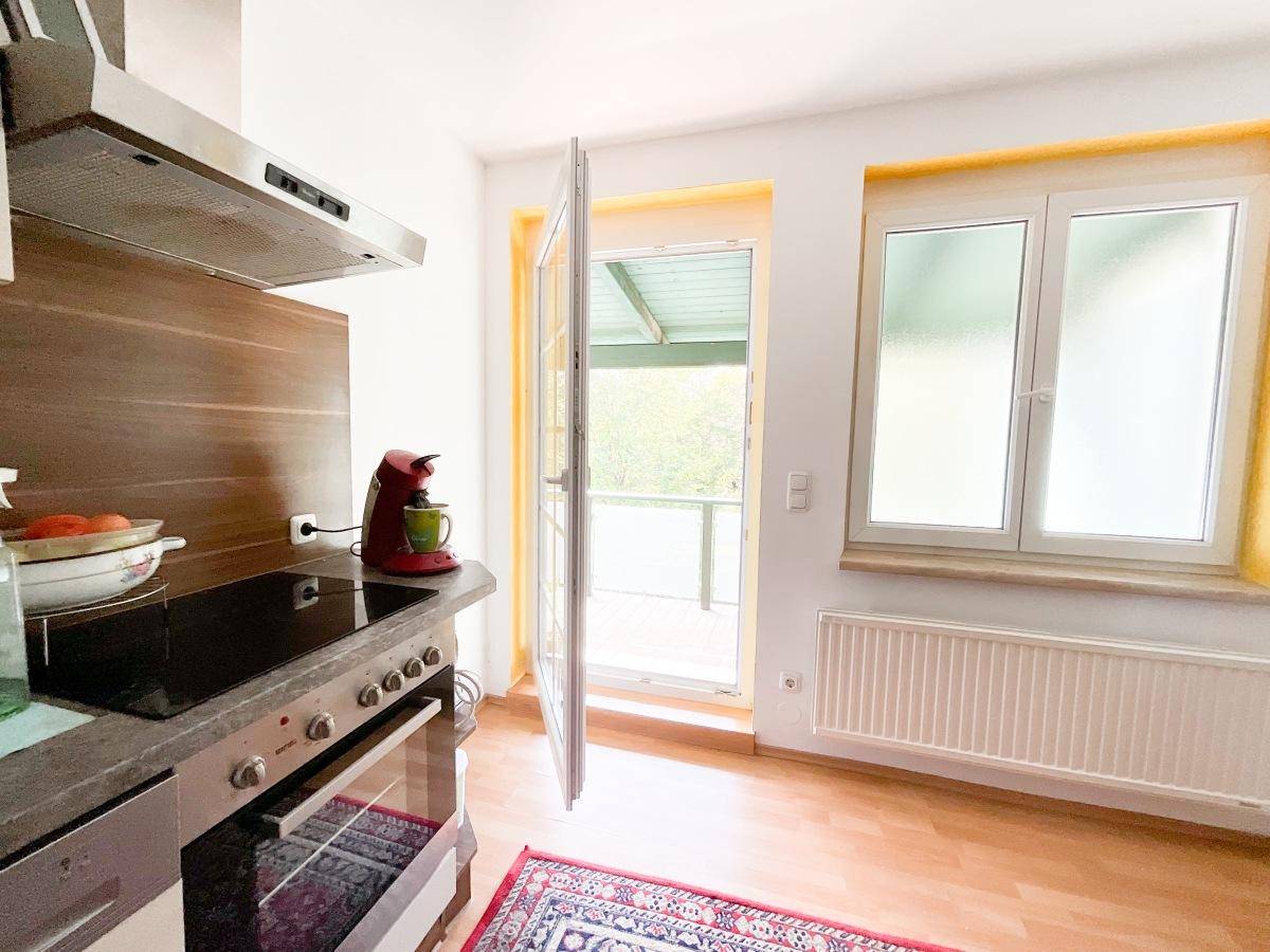 Küche mit Einbaugeräten, Kochfeld und Zugang zu einem überdachten Balkon.