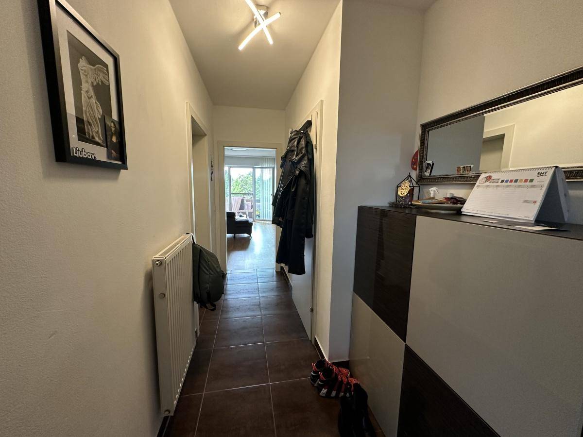 Langer Flur mit Fliesenboden und Garderobe, führt zu den verschiedenen Räumen der Wohnung.