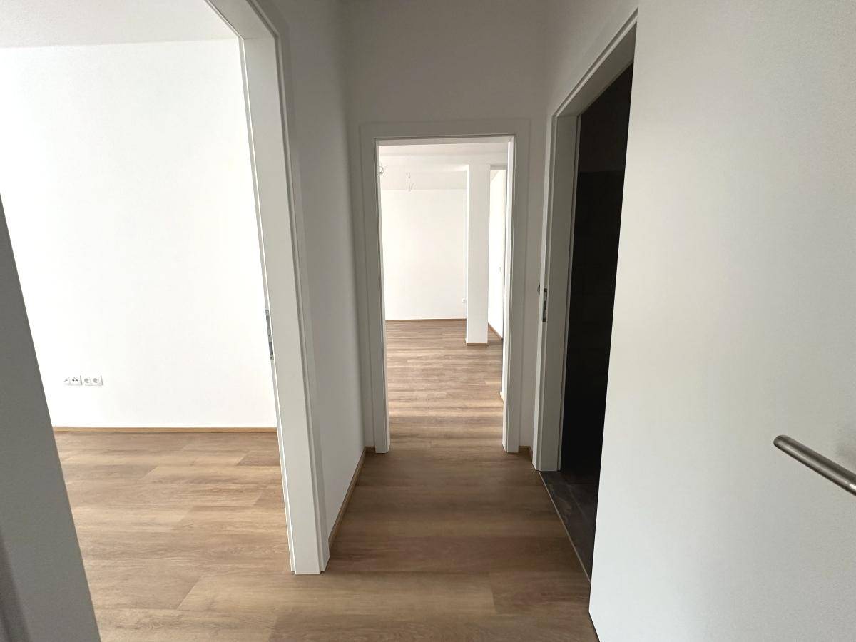 Heller Flur mit Laminatboden und mehreren Türen, die zu den verschiedenen Räumen führen.