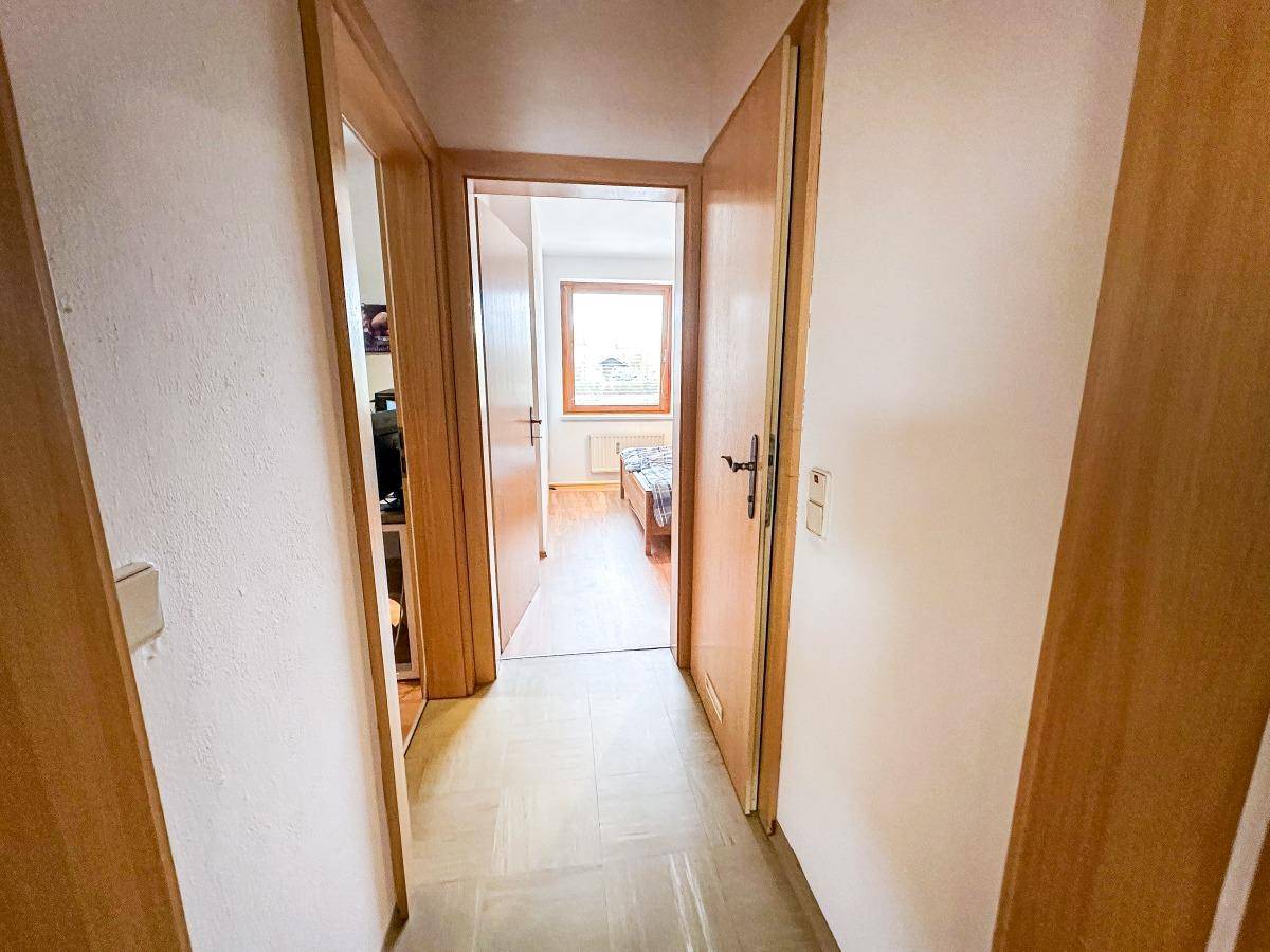 Heller Flur mit Holztüren und Zugang zu den angrenzenden Räumen.