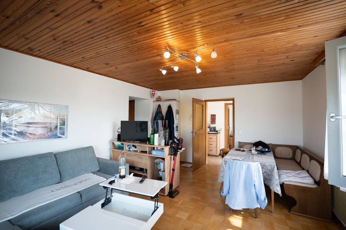 Offener Wohn- und Essbereich mit Holzbalkendecke, Sofa und Essecke.