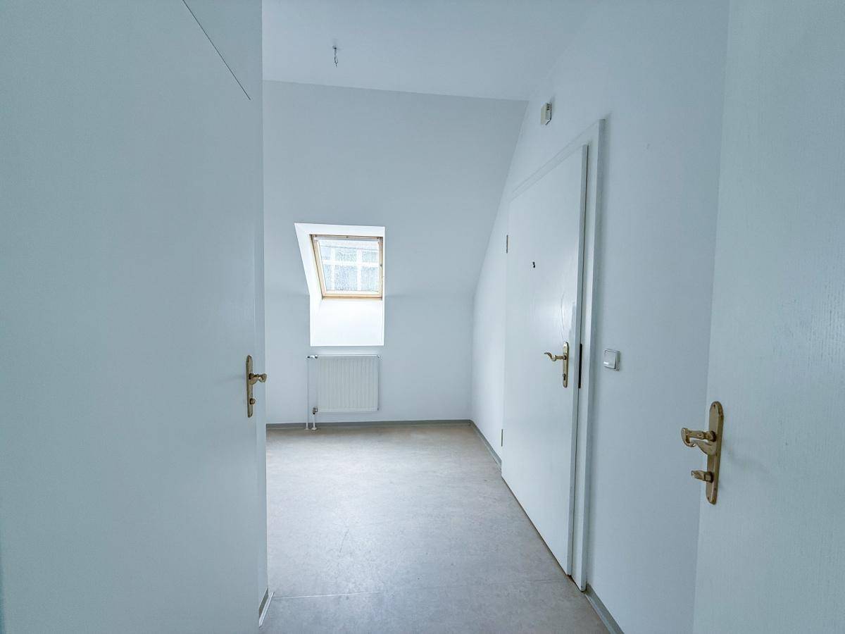 Heller Flurbereich mit Dachschräge, hellem Bodenbelag und mehreren Türen zu den angrenzenden Zimmern.
