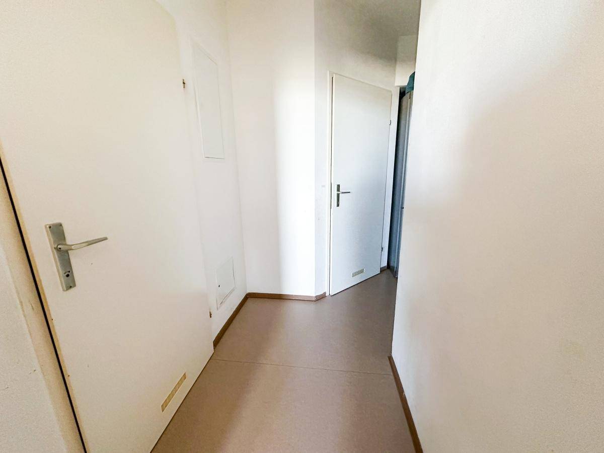 Schlichter Flur mit hellen Böden und mehreren Türen zu den Zimmern.
