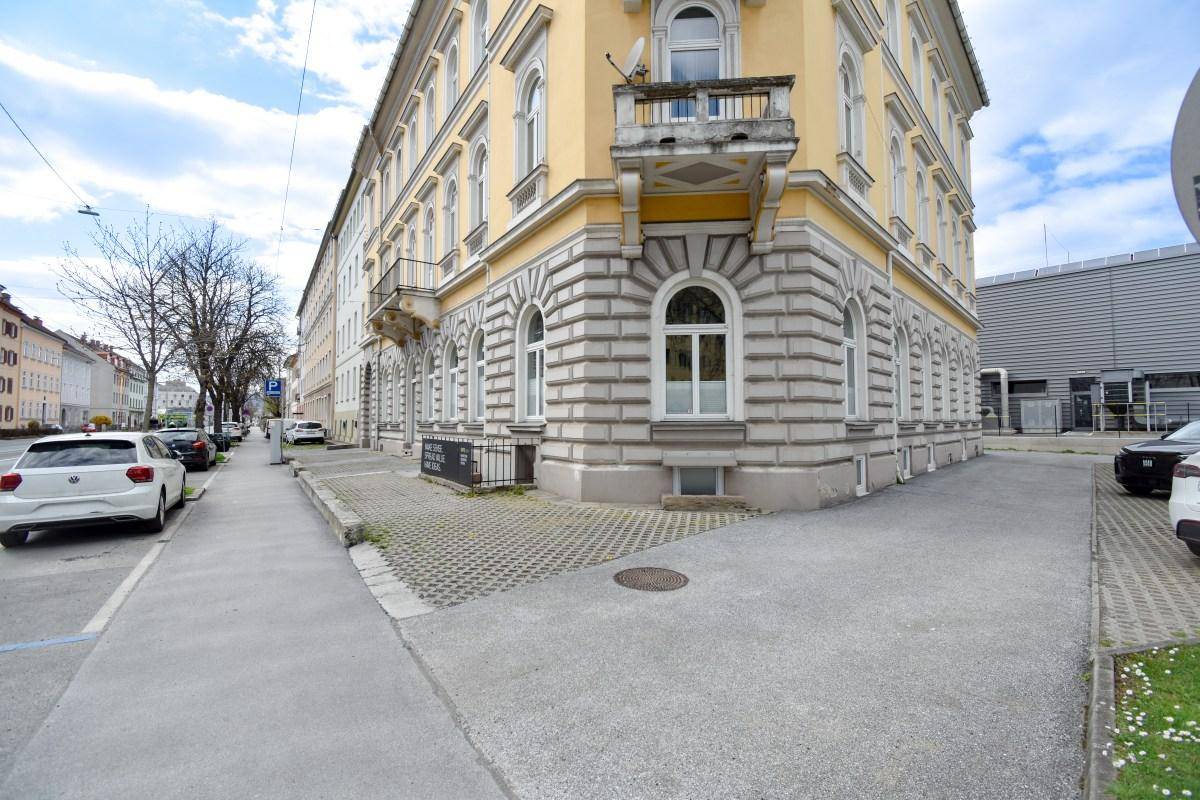 Eckansicht eines historischen Gebäudes mit Balkonen und Blick auf die Straße und umliegende Gebäude.