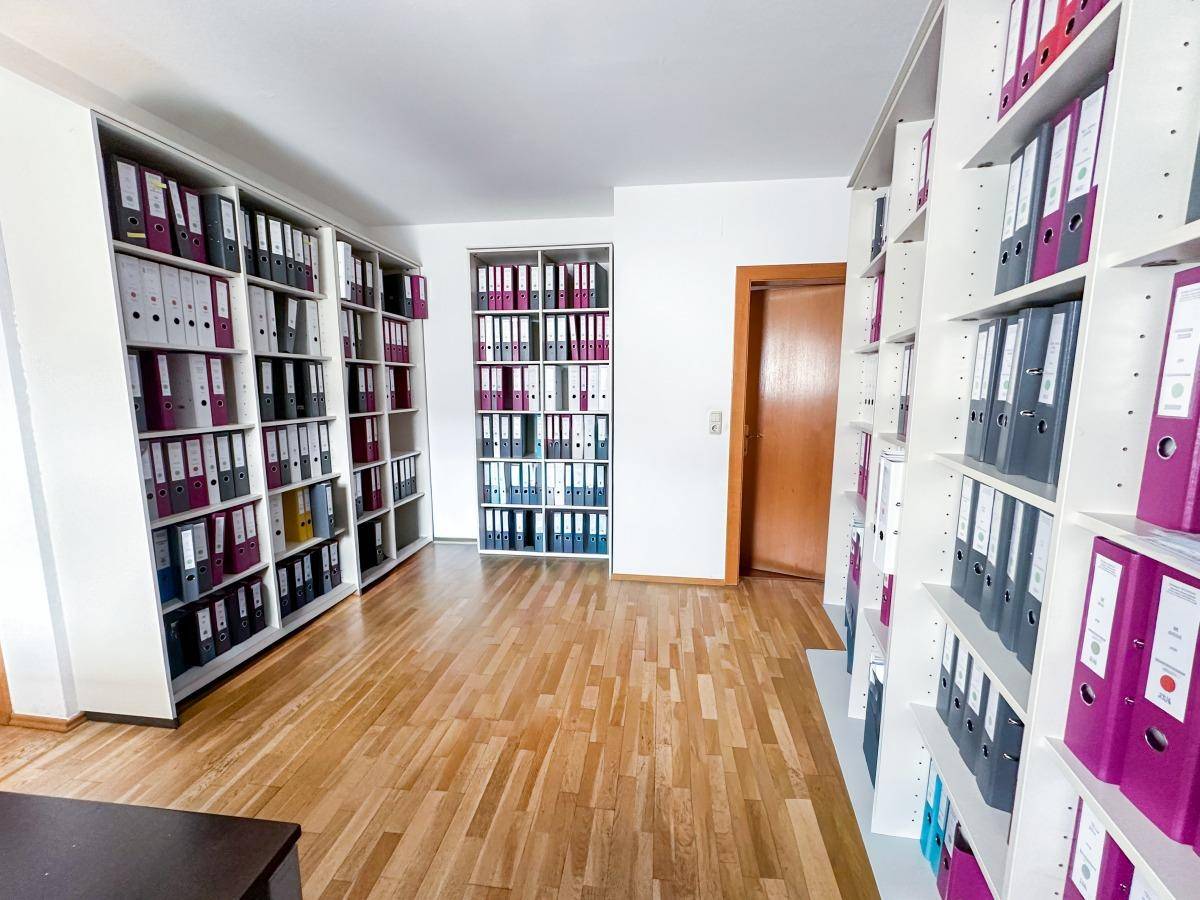 Archivraum mit zahlreichen Regalen voller Aktenordner und hellem Holzfußboden.
