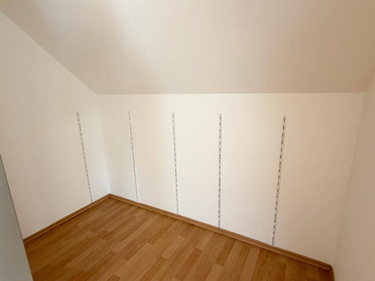 Praktischer Abstellraum im Dachgeschoss mit Laminatboden und Regalschienen für flexible Lagerung.