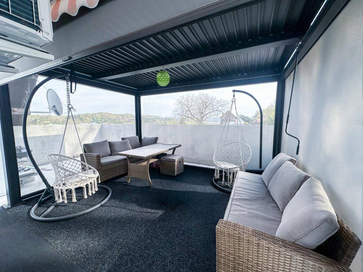 Gemütliche überdachte Terrasse mit Rattanmöbeln und Hängesesseln, ideal zum Entspannen im Freien.