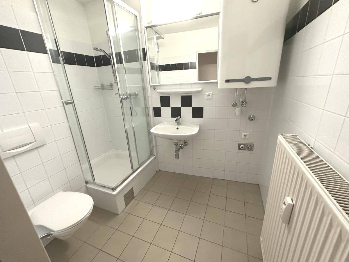 Modernes Badezimmer mit Duschkabine, WC, Waschbecken und schwarz-weißen Fliesen.