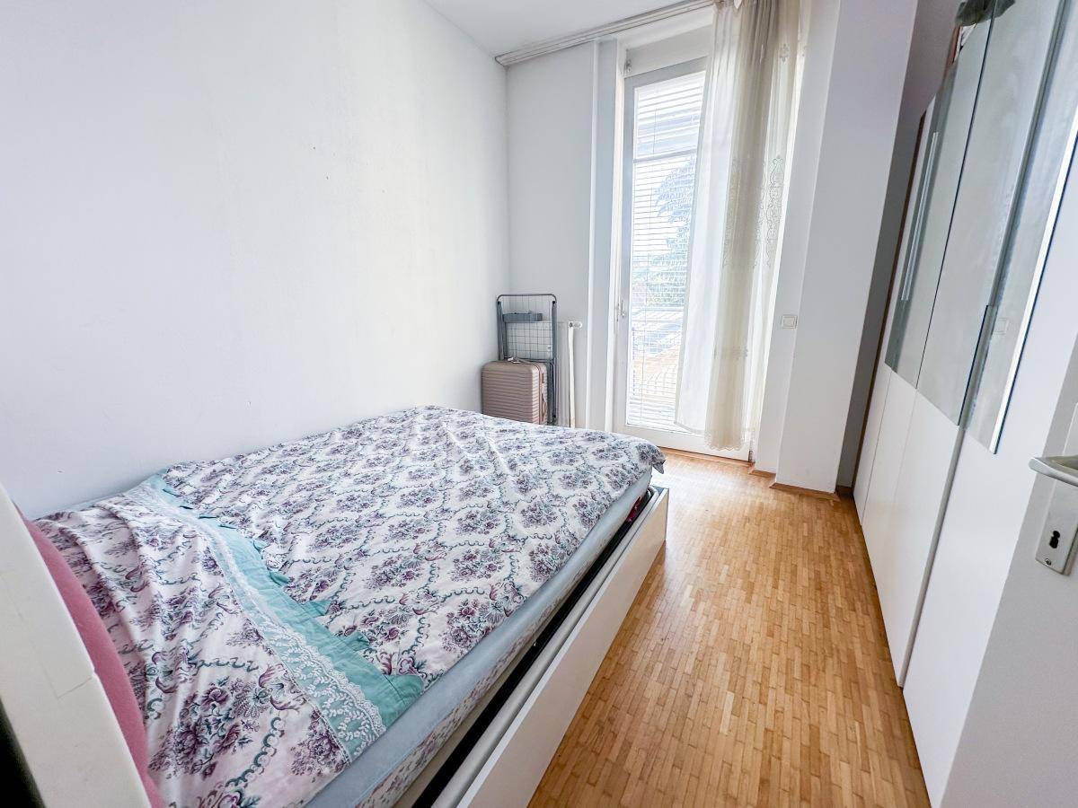 Schlafzimmer mit Parkettboden, Bett und Zugang zu einem Außenbereich.