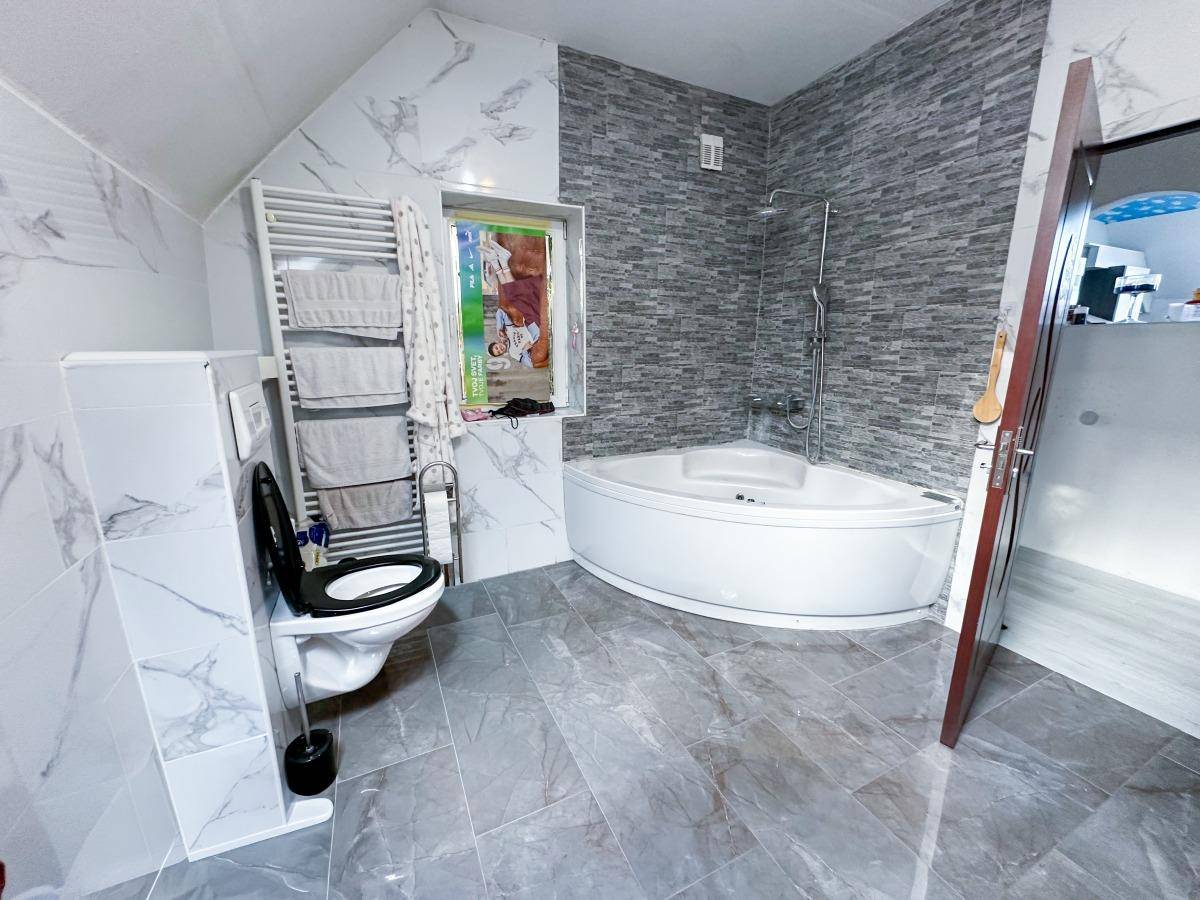 Modernes Badezimmer mit Eckbadewanne, Wand-WC und beheiztem Handtuchhalter.