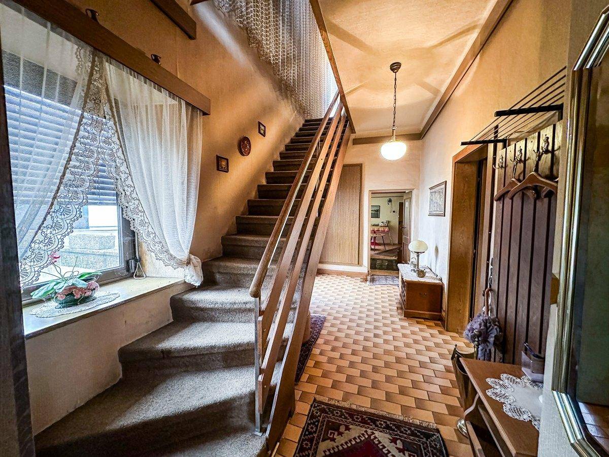 Geräumiger Flur mit Teppichboden auf der Treppe und Fliesen im Eingangsbereich.