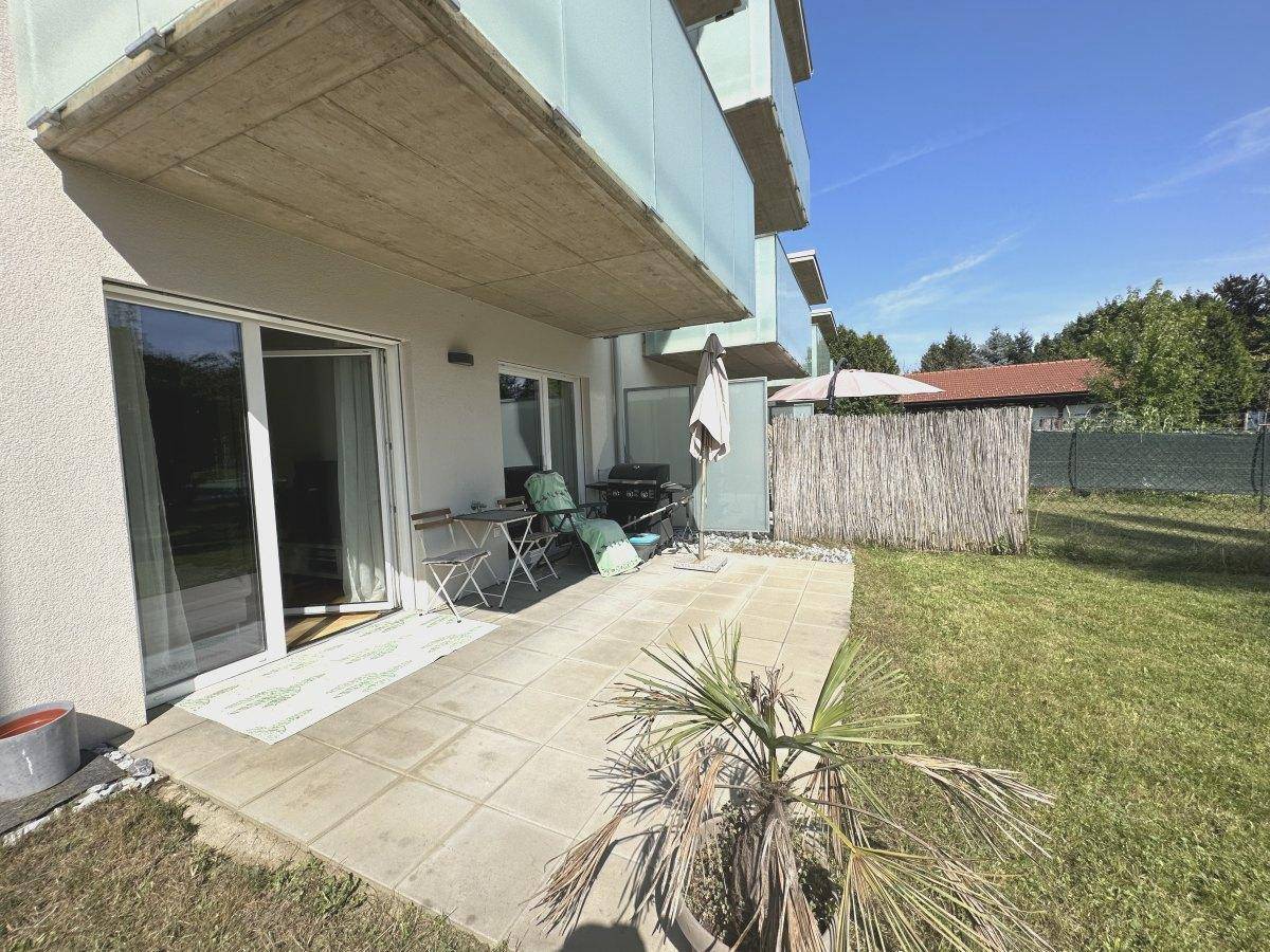 Sonniger Terrassenbereich mit Gartenmöbeln, Grill und direktem Zugang zum Rasen.