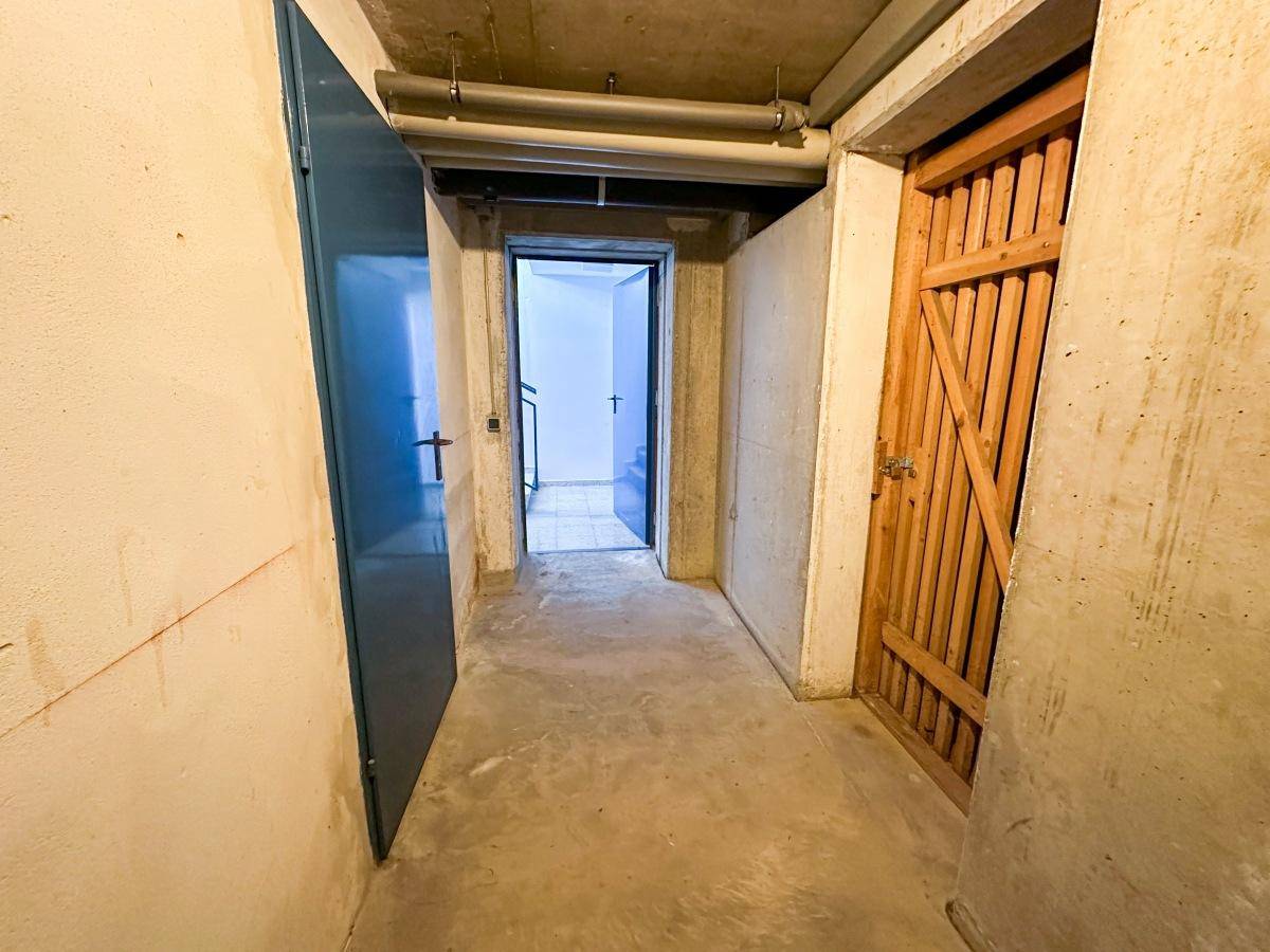 Kellerflur mit Zugang zu verschiedenen Abstellräumen und Betonboden.