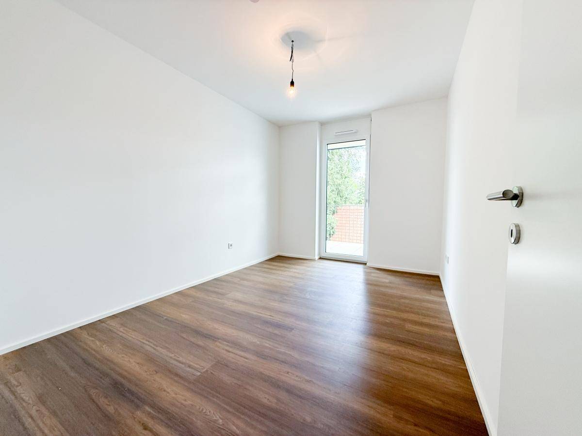 Geräumiges Schlafzimmer mit Laminatboden und Zugang zu einem Außenbereich.