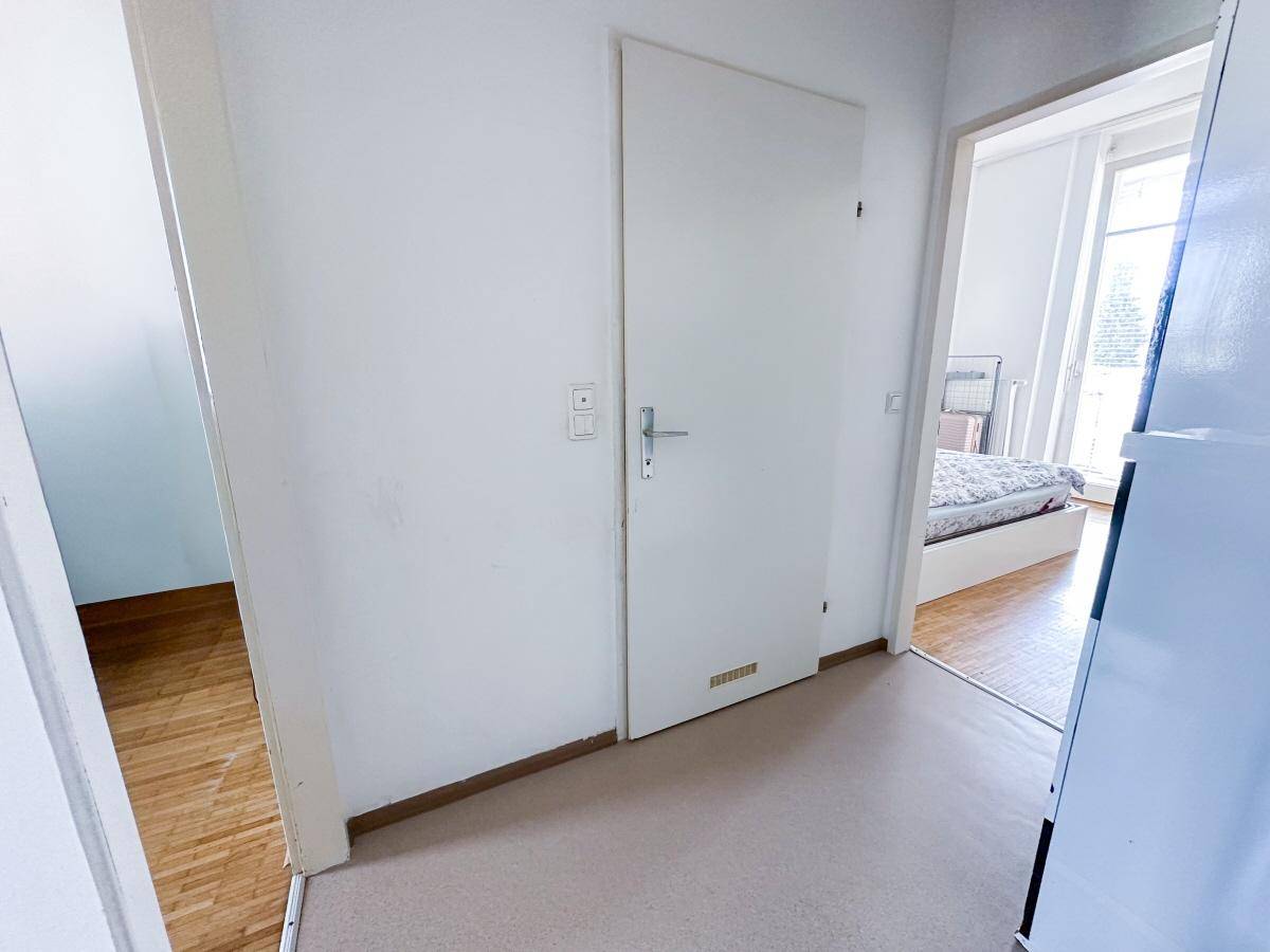 Heller Flur mit weiß gestrichenen Wänden und Türen zu angrenzenden Räumen.