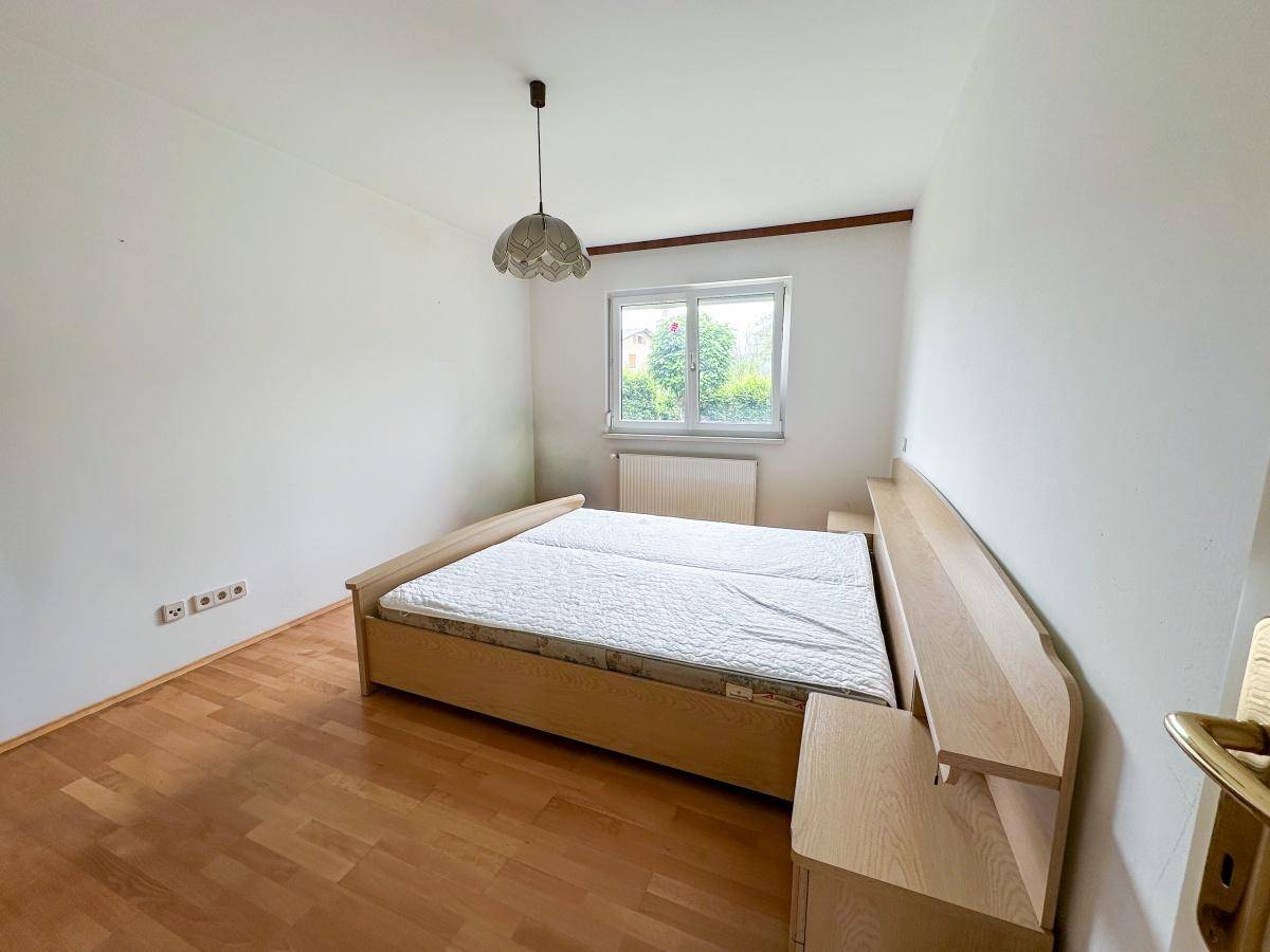 Helles Schlafzimmer mit Holzbett, Nachttischen und Parkettboden, bereit zur individuellen Gestaltung.