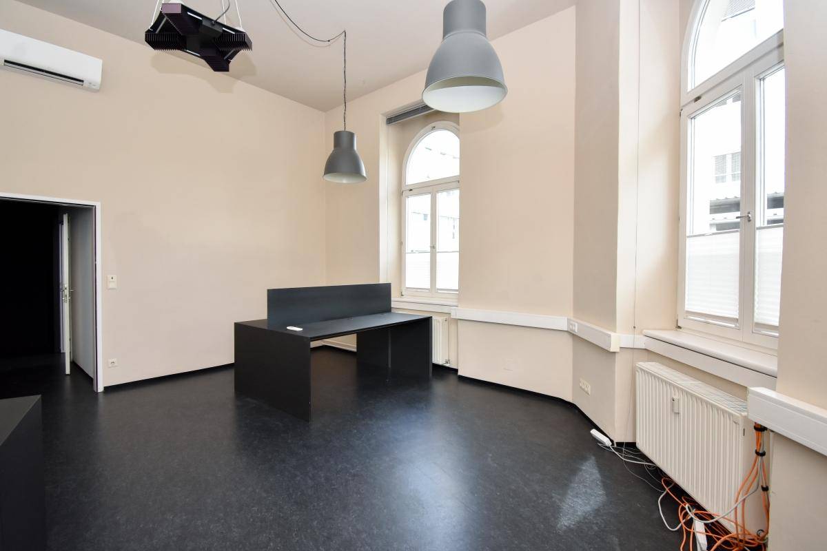 Heller Büroraum mit einem Arbeitsplatz, hohen Decken und einer Klimaanlage an der Wand, bietet angenehmes Klima.