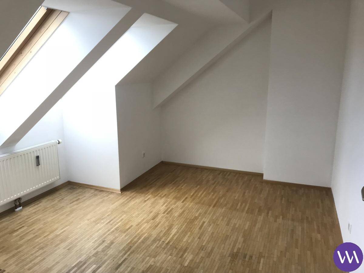 Helles Zimmer im Dachgeschoss mit Dachfenstern, Heizkörper und Parkettboden.